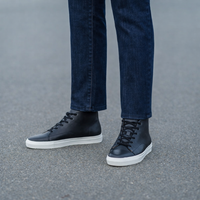 Men's black leather high top sneakers with white rubber sole worn with dark denim jeans
