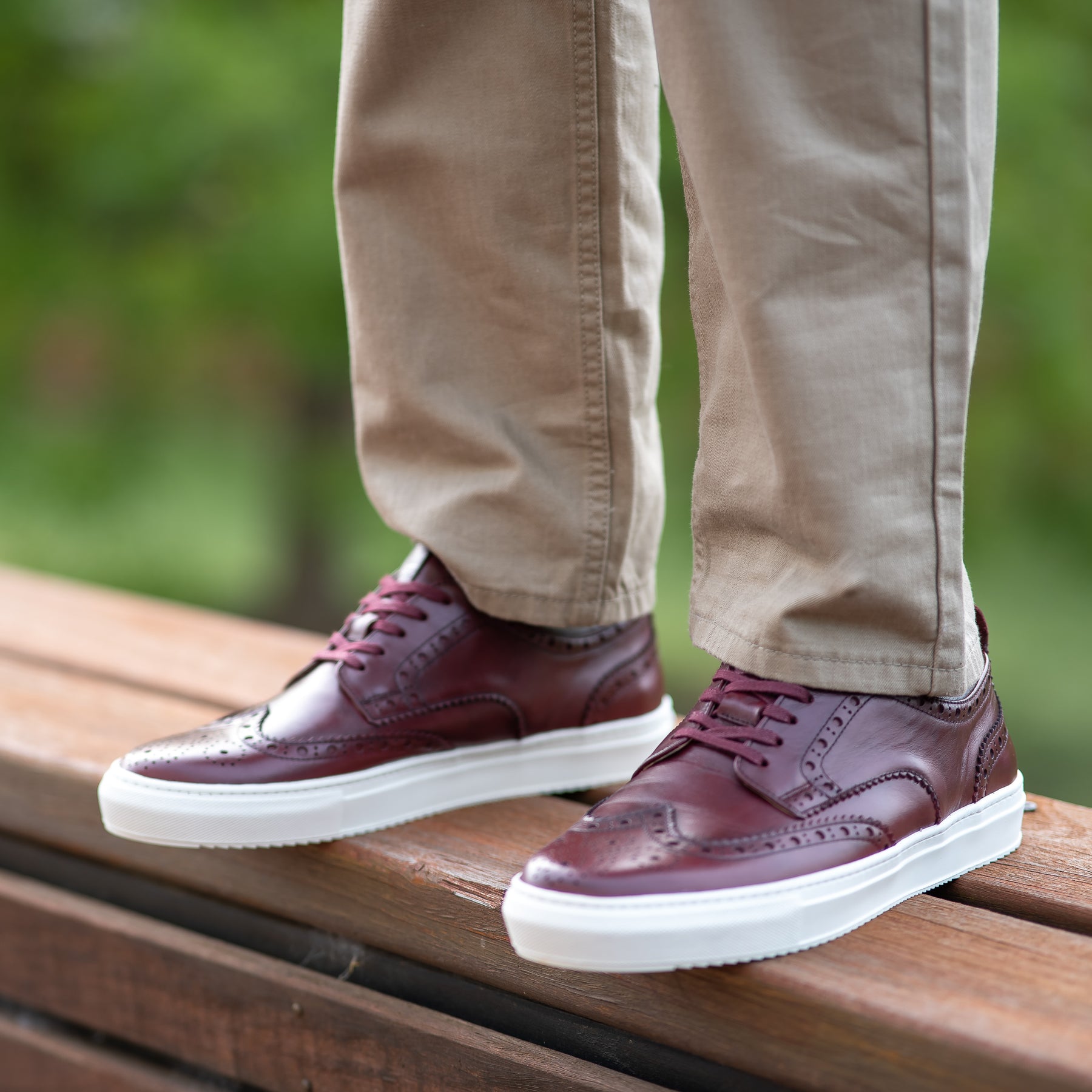 Brogue sneakers in burgundy with beautiful perforation, worn with light brown Khaki trousers and t-shirt