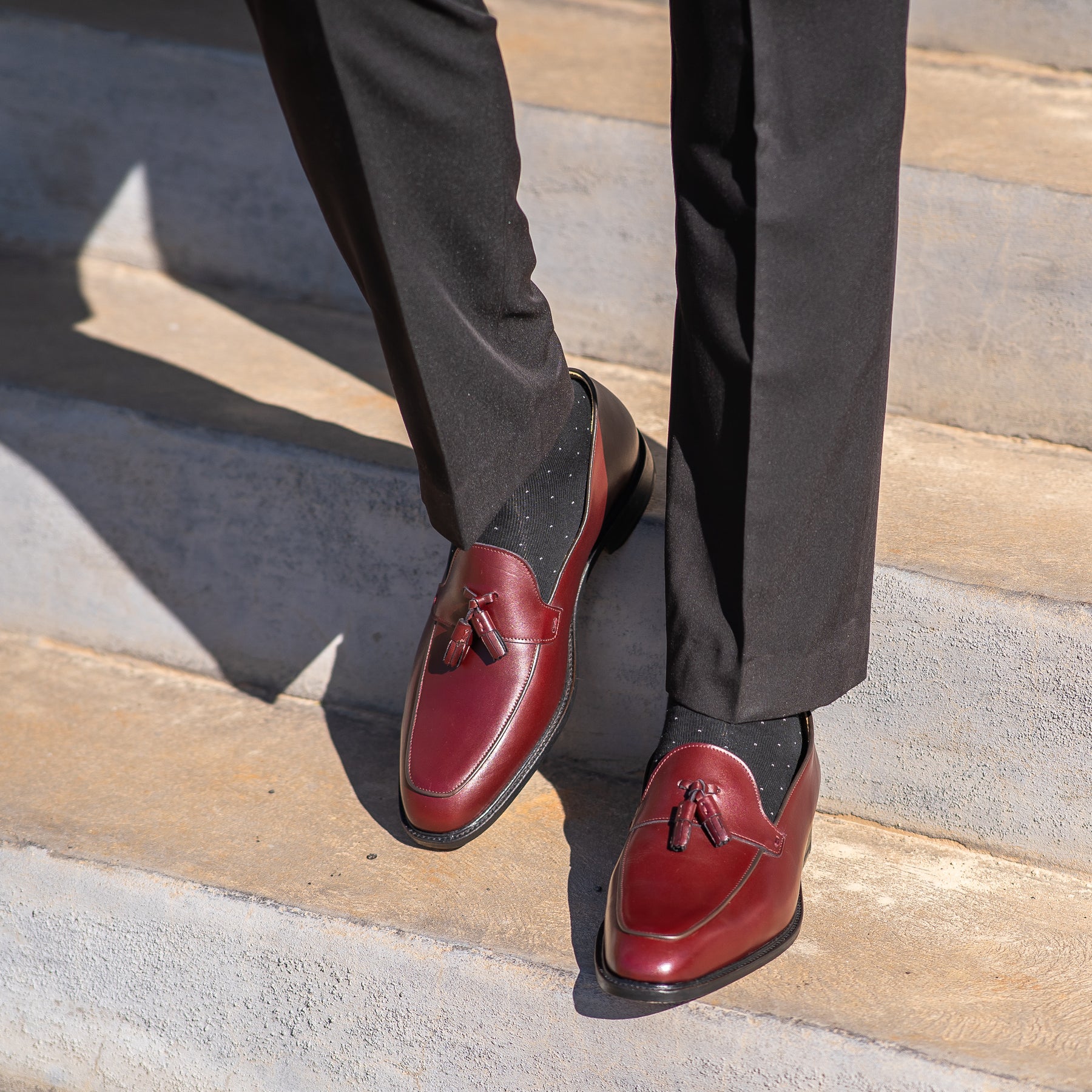 Mens burgundy tassel loafers made using blake rapid stitched construction and worn black cotton socks