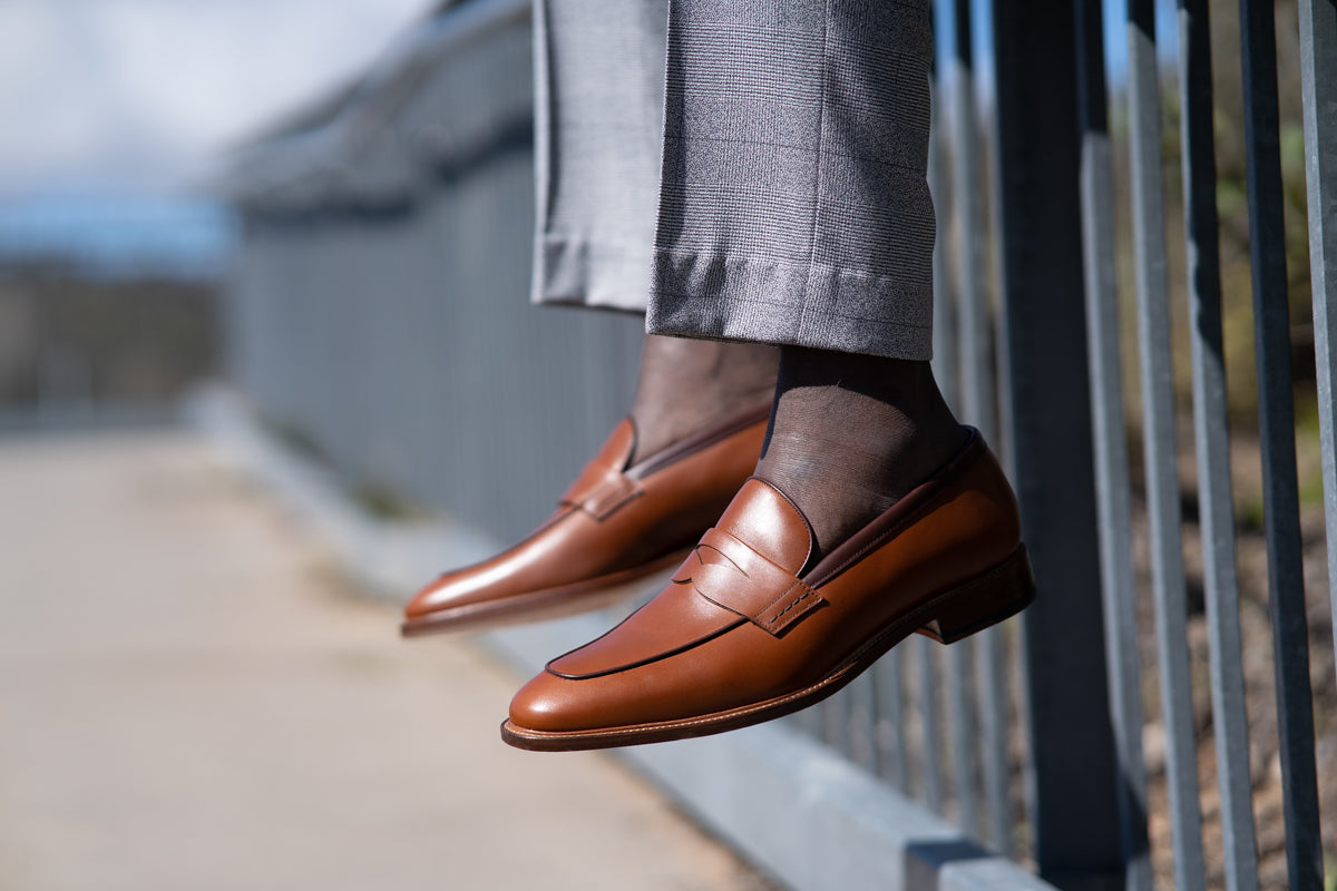 Mens tan penny loafers with blake rapid stitched construction worn blue khaki trousers and printed shirt without socks