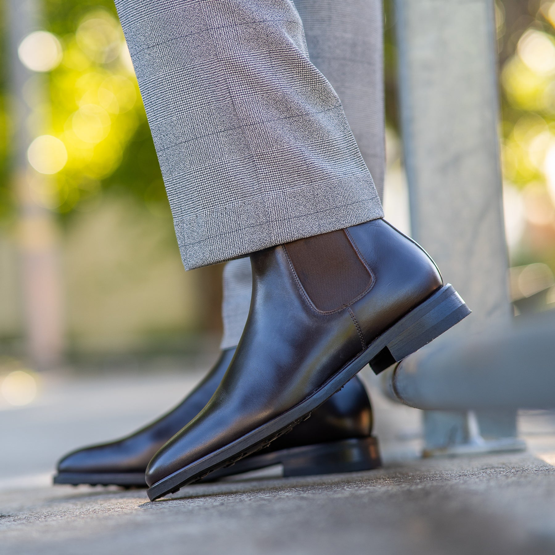 Mens leather chelsea boots paired with grey trousers and black jacket