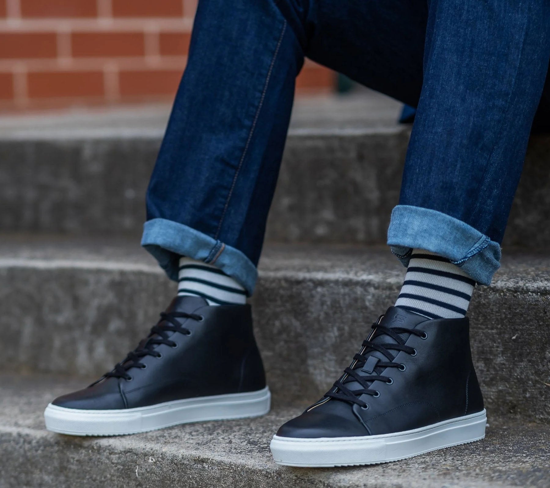 Black high top sneakers paired nicely with jeans and stripped socks.