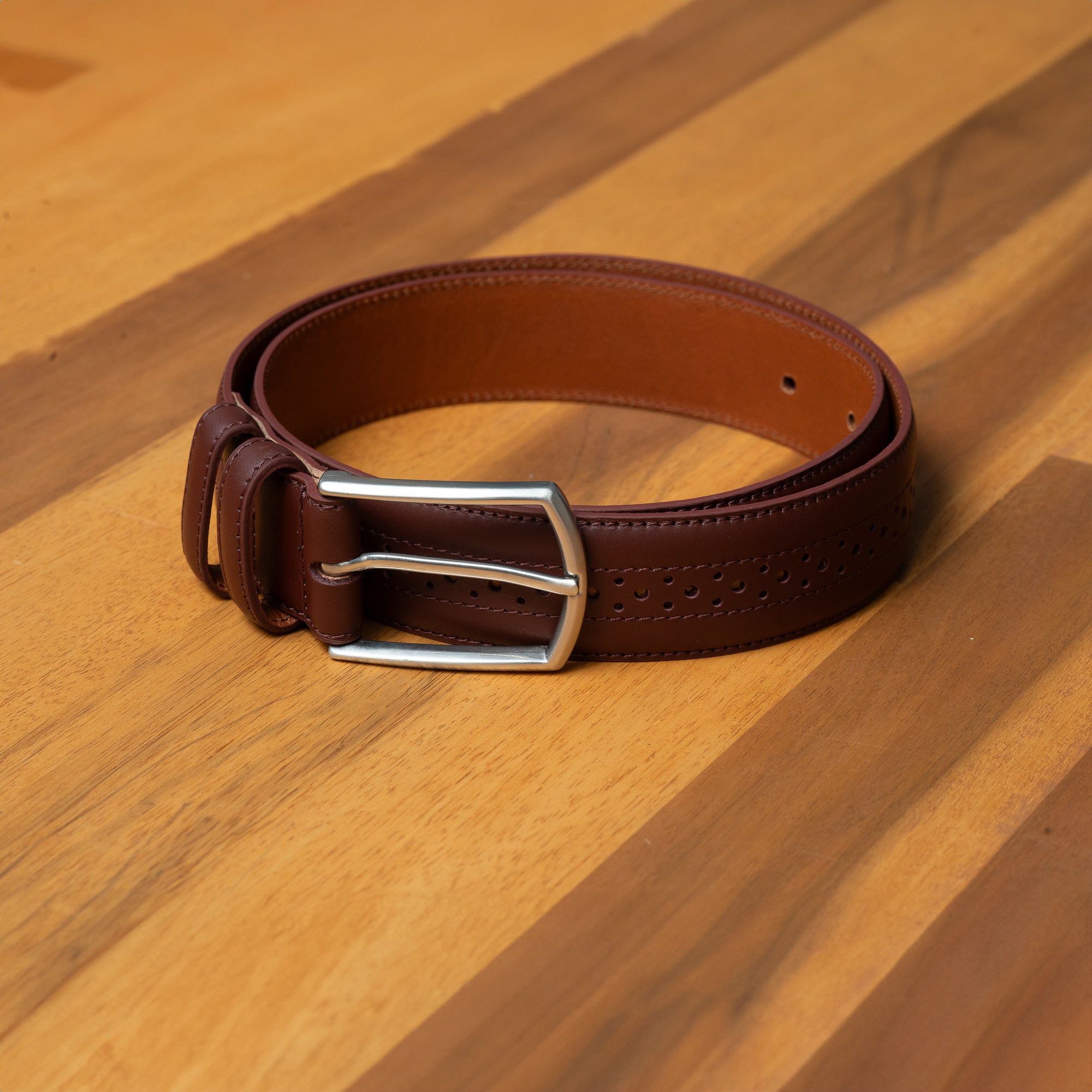 Burgundy leather belt. Brogue detail for men who pair suits with wingtip shoes.