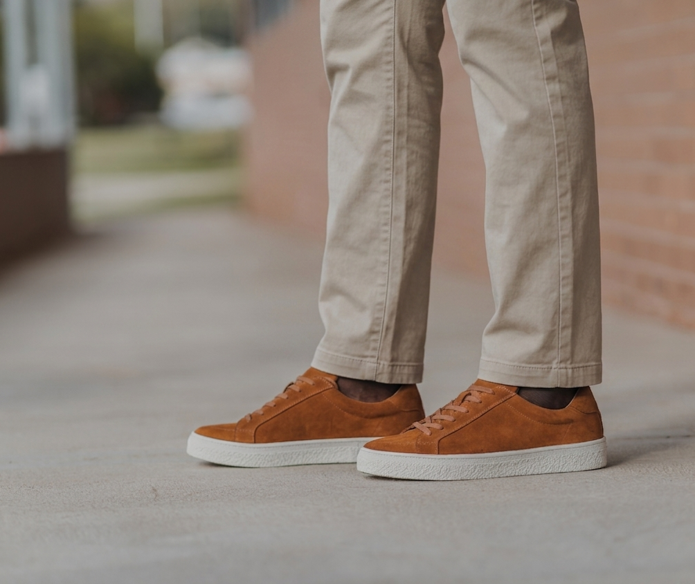 Mens tan suede low top sneakers worn with stone chinos. A simple smart casual outfit for everyday wear.