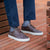 The Alpha low top wingtip sneakers in dark brown leather, paired with blue khaki and polo shirt