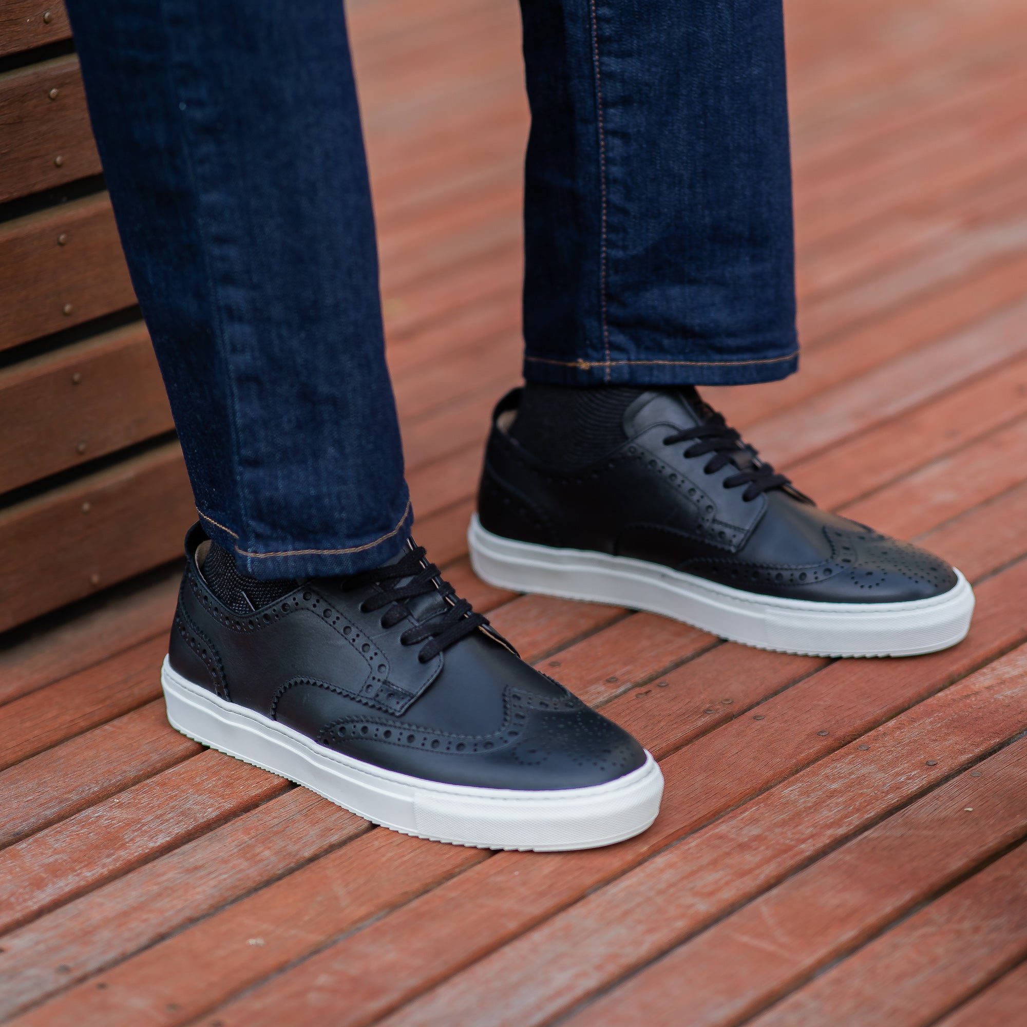 The Alpha men’s full brogue sneakers in black leather, decorated with perforation worn with slim jeans and black socks.