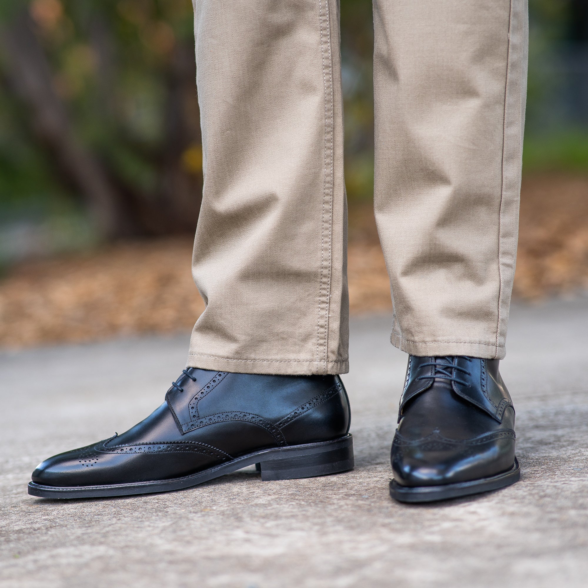 Biege smart jeans paired with the mens black wingtip dress boots decorated with brogues perforation on the upper leather