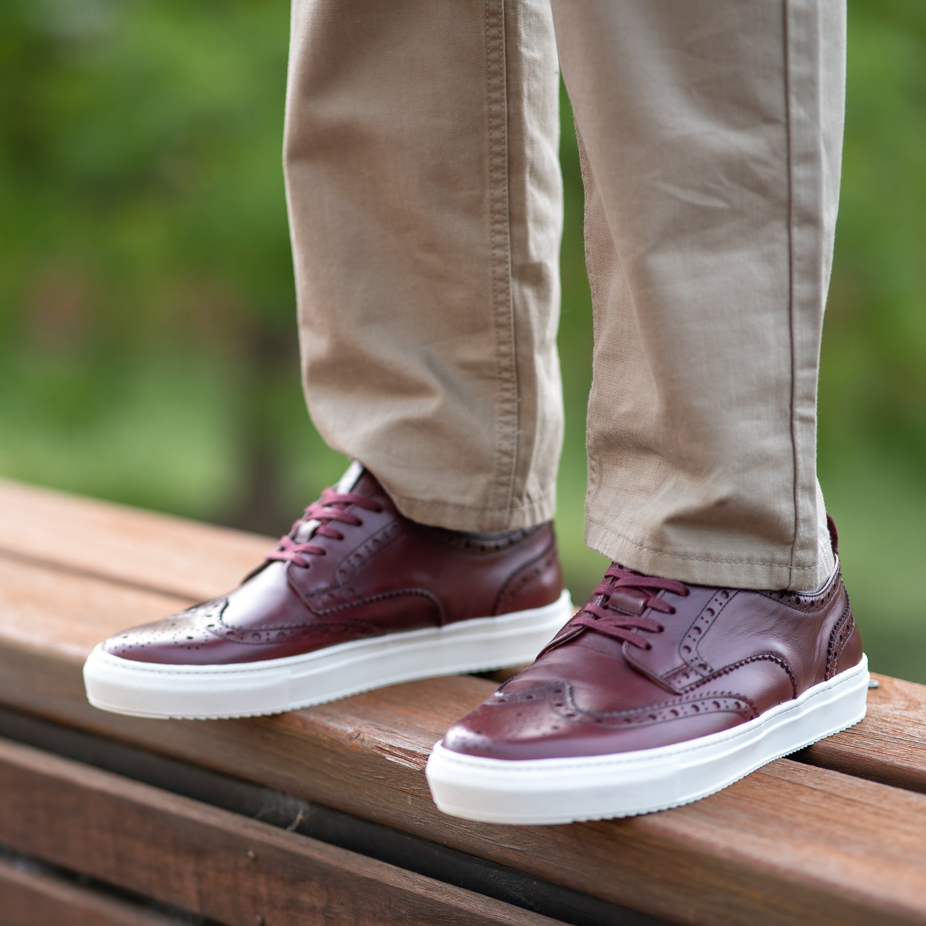 Brogue sneakers in burgundy with beautiful perforation, worn with light brown Khaki trousers and t-shirt