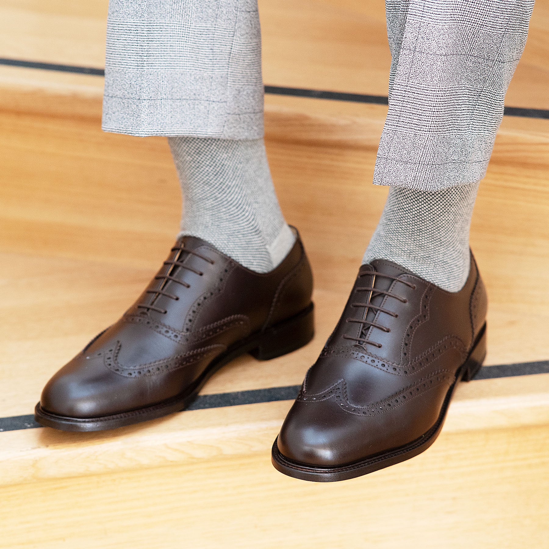 Mens dark brown brogue shoes paired with premium tailored jacket with grey cotton socks.