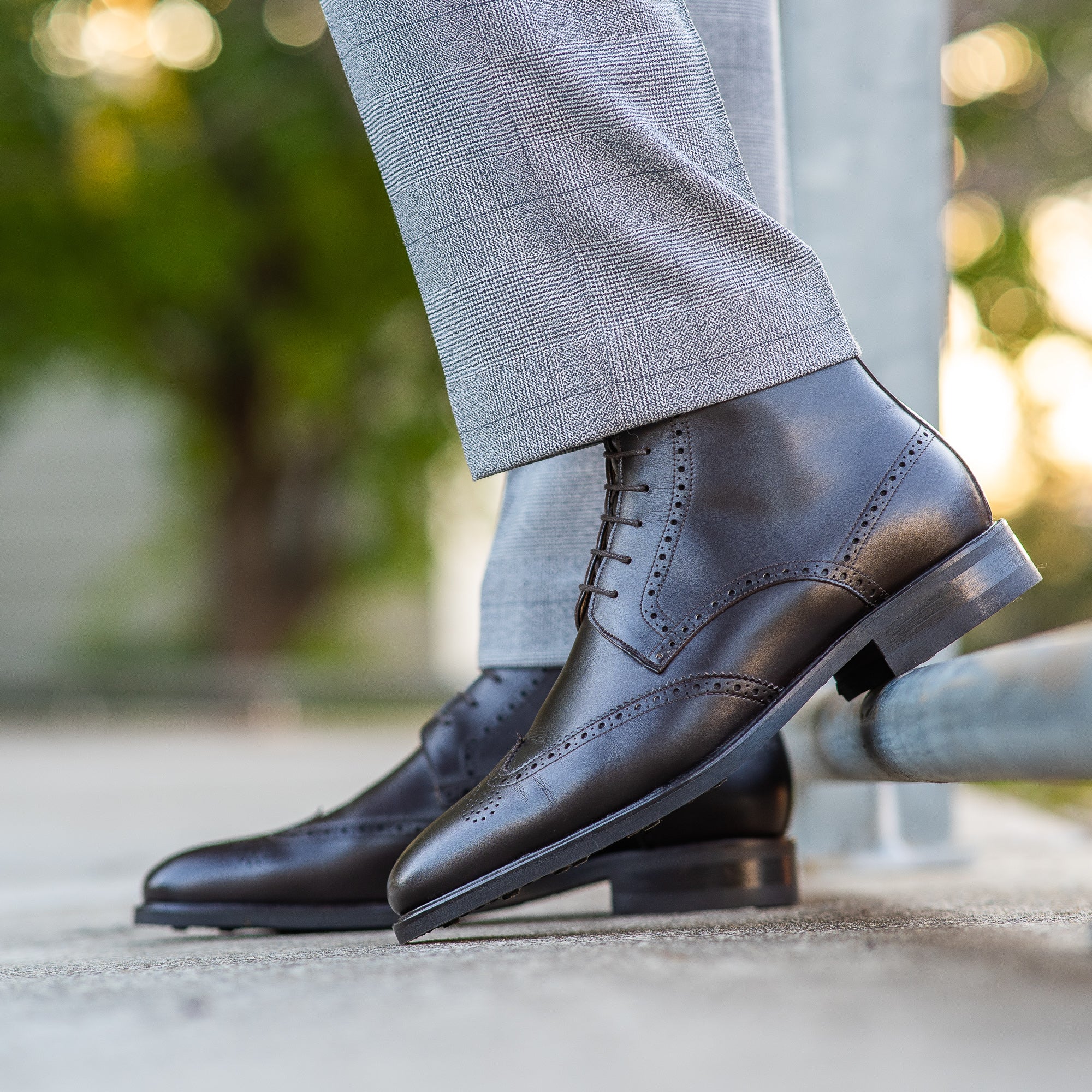 Mens brown brogue boots featuring wingtip design and paired with suit for professional look