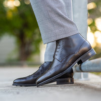 Mens brown wingtip brogue boots featuring wingtip design and paired with suit for professional look