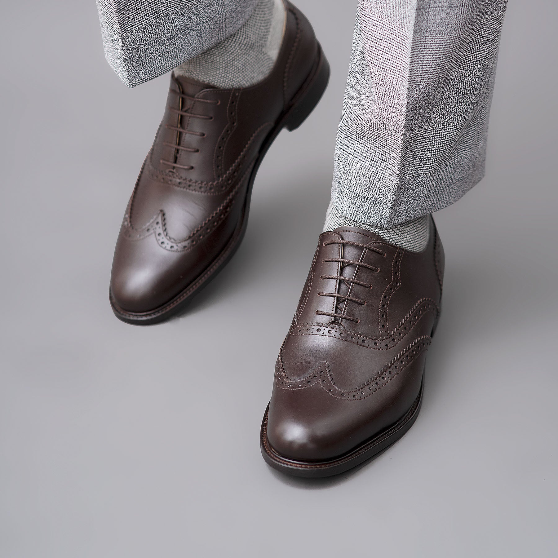 Mens brown brogues shoes with wingtip design paired with high quality suit and cotton shirt