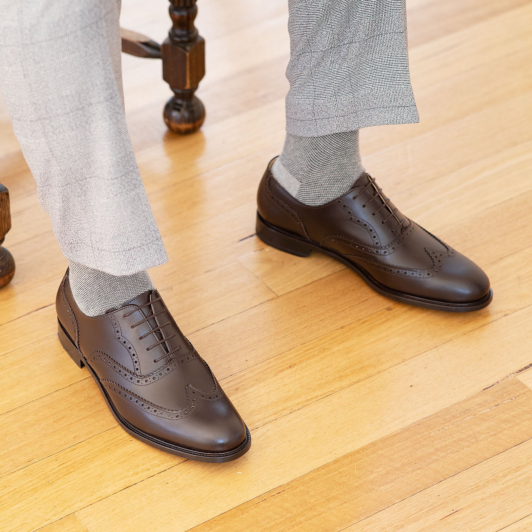 Mens brown wingtip shoes with broguing paired with smart ankle pants and bespoke shirt