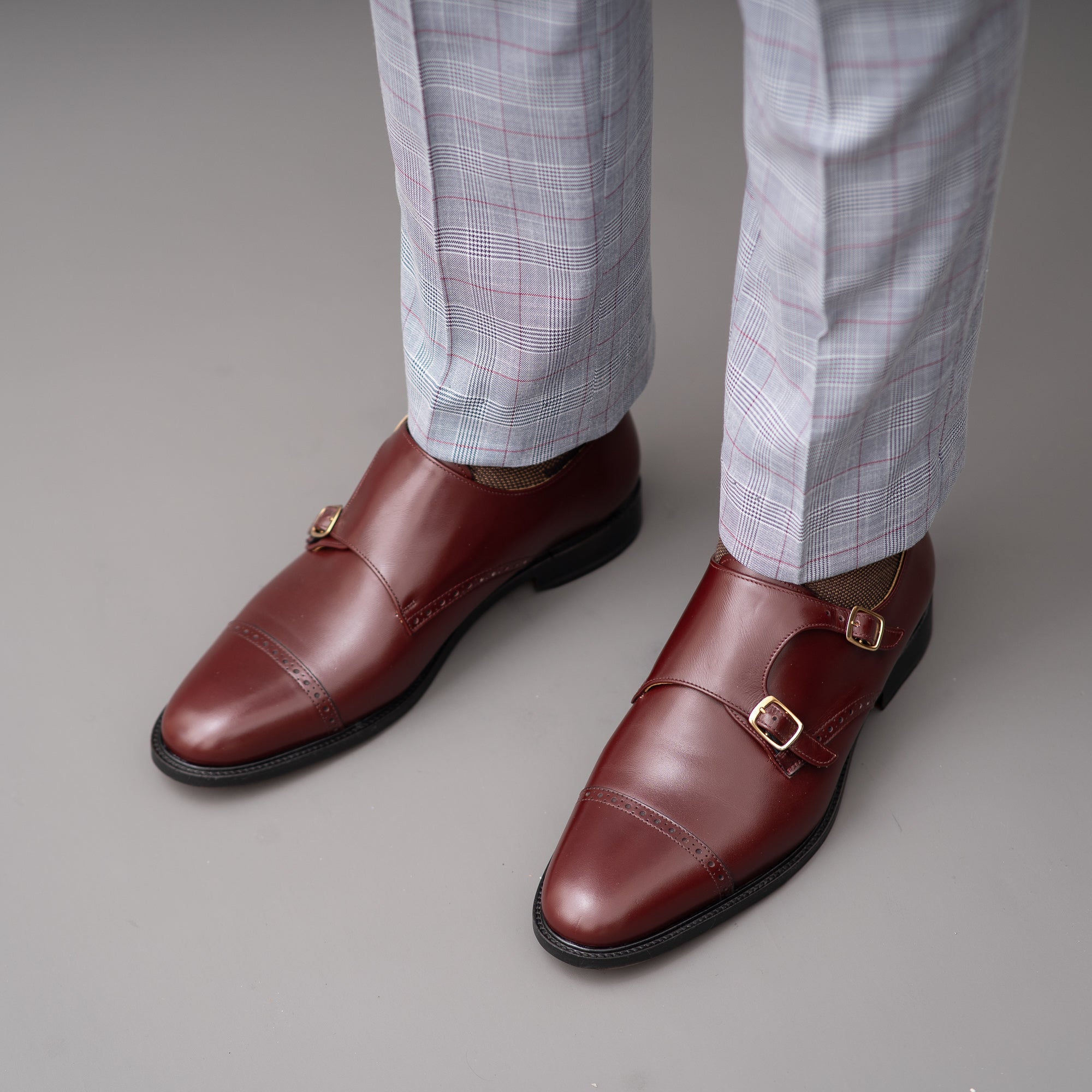 Men's buckle shoes in burgundy worn with striped tailored fit dress pant.