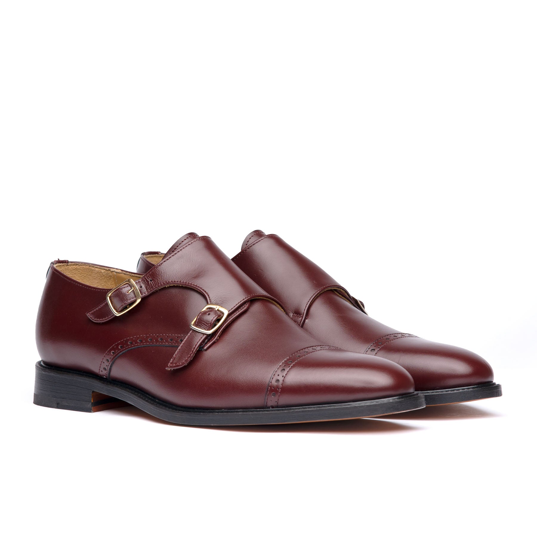 Burgundy monk strap shoes with offset buckles and leather sole