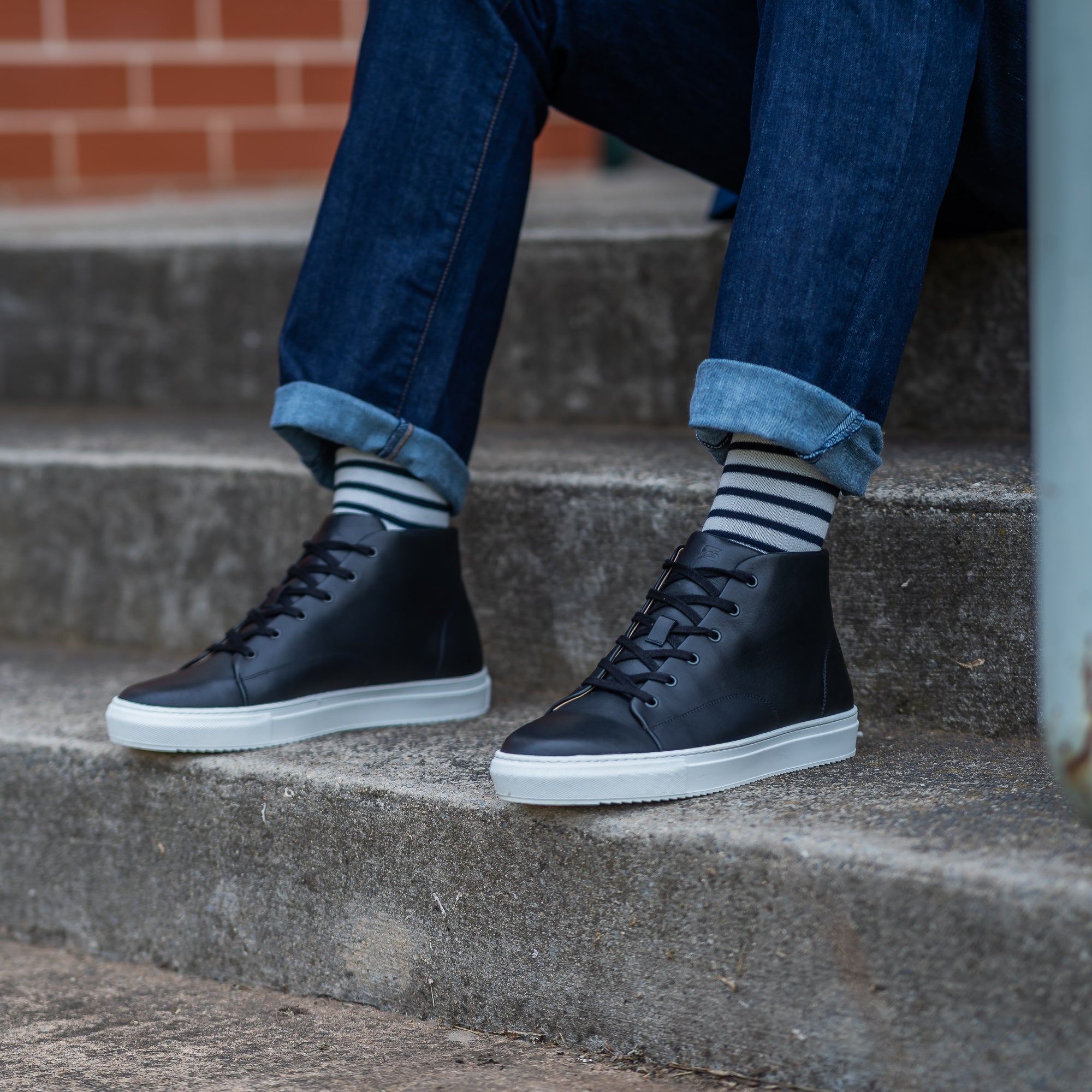 White and black high top sneakers styled with blue slim denim and 100% striped socks.